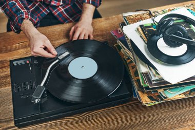 Vinil plaktan müzik dinleyen bir adam. Plak çalar üzerinde analog diskten müzik çalmak. Eski koleksiyonumdan müziğin tadını çıkarıyorum. Evde dinleniyorum. Retro ve antika. Müzik tutkusu