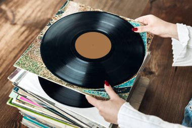 Vinil plak çalıyorum. Vinil pikaptan müzik dinliyordum. Retro ve klasik müzik tarzı. Analog LP albüm tutan bir kadın. Eski plaklar yığını. Müzik koleksiyonu. Müzik tutkusu