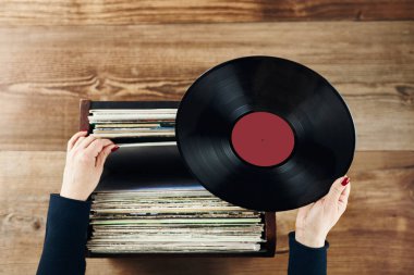 Playing vinyl records. Listening to music from vinyl record player. Retro and vintage music style. Woman holding analog LP record album. Stack of old records. Music collection. Music passion