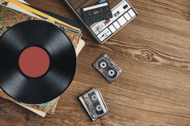 Vinil plaklar, kasetler ve ahşap masada kaset kaydedici. Retro müzik tarzı. 80 'lerin müzik partisi. Eski tarz. Analog ekipmanları. Stereo sesi. Geçmişe dönelim.