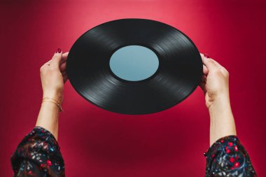 Elinde plak plağı tutan bir kadın. Müzik tutkusu. Analog kayıtlardan müzik dinlemek. Plak çalar üzerinde analog diskten müzik çalmak. Eski koleksiyonumdan müziğin tadını çıkarıyorum. Retro ve antika. Stereo sesi. Analog sesi