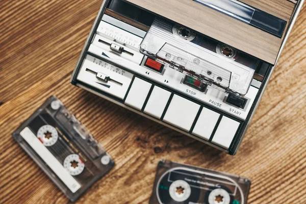 Compact cassette tapes and cassette recorder on wooden table. Retro music style. 80s music party. Vintage style. Analog equipment. Stereo sound. Back to the past