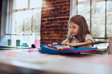 Ödev yapan, öğrenen, resim çizen, okul kütüphanesinde yapboz yapan bir kız. İlkokul öğrencisi, yapboz kitabıyla meşgul. Akıllı kız kitaptan öğreniyor. Günlük okumanın faydaları. Çocuk merakı