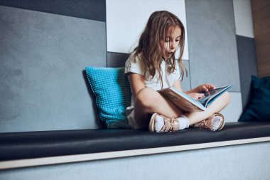 Kitap sayfasına bakan liseli kız şaşırdım. Okul kütüphanesinde çocuk kitapları okuyor. İlkokul öğrencisi kitapla ilgileniyor. Ödev yapan çocuk. Akıllı kız kitaptan öğreniyor. Günlük okumanın faydaları. Çocuk merakı