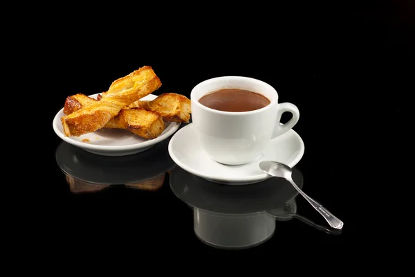 Een kopje chocolade met bladerdeeg banden, geïsoleerd op zwart — Stockfoto