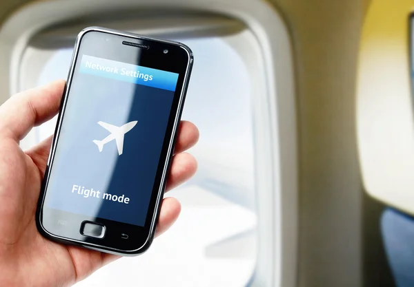 Mano sosteniendo el teléfono inteligente dentro del avión —  Fotos de Stock