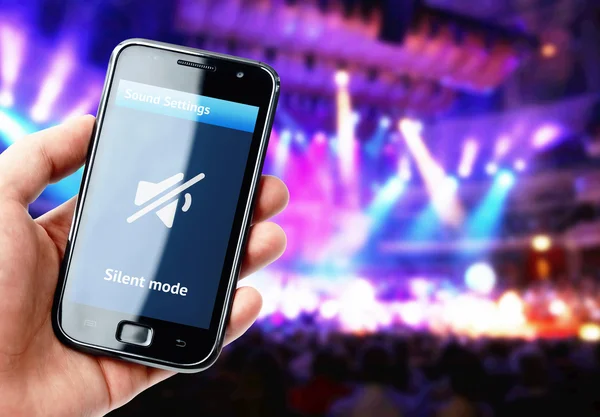 Mão segurando smartphone com som mudo durante o concerto — Fotografia de Stock