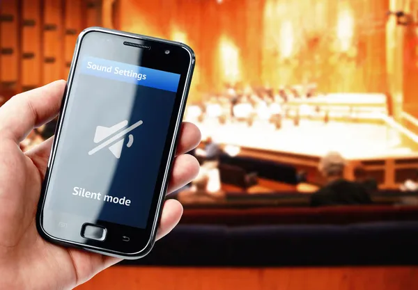 Hand som håller smartphone med stum ljud under konsert — Stockfoto