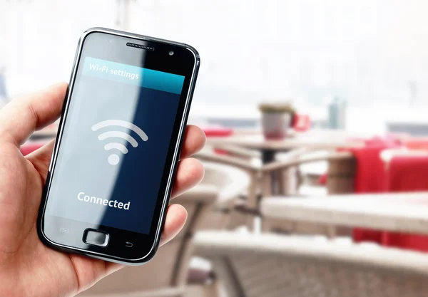 Hand holding smartphone with wi-fi connection in cafe — Stock Photo, Image