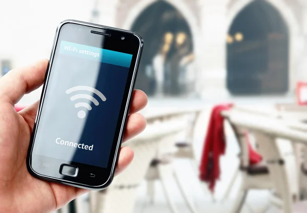 Χέρι που κρατά το smartphone με wi-fi σύνδεση στο café — Φωτογραφία Αρχείου