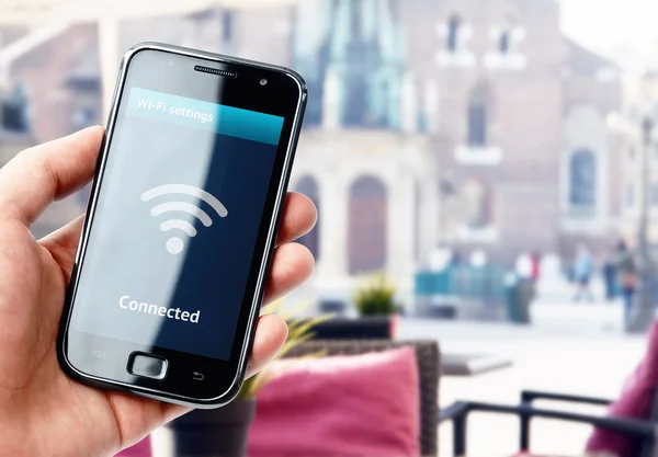 Hand holding smartphone with wi-fi connection in cafe — Stock Photo, Image