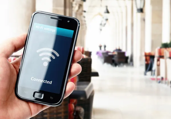 Hand holding smartphone with wi-fi connection in cafe — Stock Photo, Image