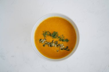 Beyaz arka planda balkabağı çorbası. Üst görünüm