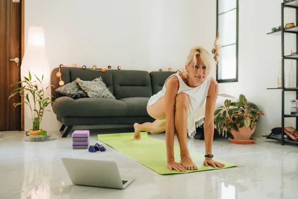ブロンド女性座っている床とトレーニングによってオンラインコース見てのラップトップ — ストック写真