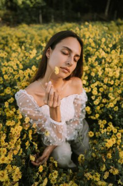 Genç ve çekici bir kadın Chiang Mai 'deki sarı çiçek tarlasında eğleniyor.
