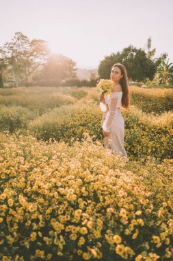 Genç ve çekici bir kadın Chiang Mai 'deki sarı çiçek tarlasında eğleniyor.