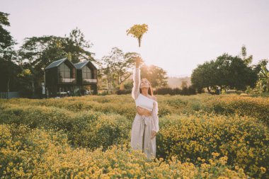 Genç ve çekici bir kadın Chiang Mai 'deki sarı çiçek tarlasında eğleniyor.