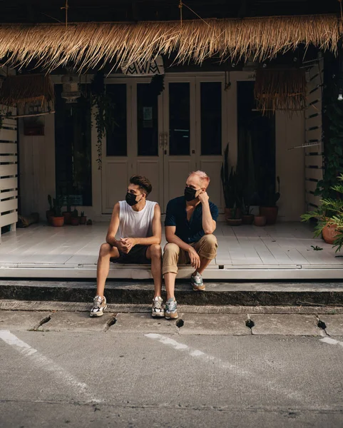 Gay Couple spend time together outdoors. Homosexual couple sitting outdoors