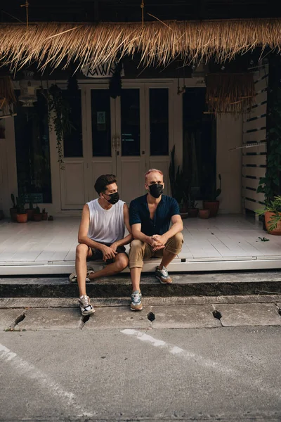 Gay Couple spend time together outdoors. Homosexual couple sitting outdoors