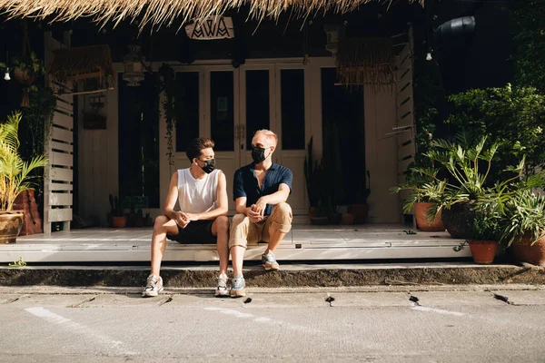 Gay Couple spend time together outdoors. Homosexual couple sitting outdoors