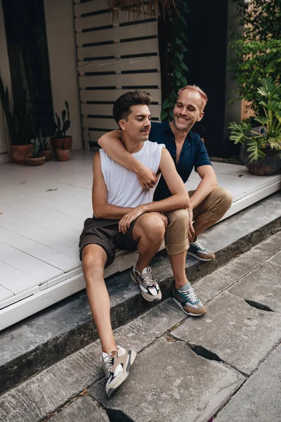 Gay Couple spend time together outdoors. Homosexual couple sitting outdoors