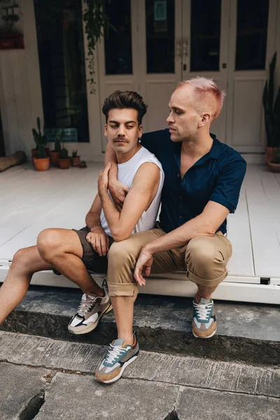Gay Couple spend time together outdoors. Homosexual couple sitting outdoors
