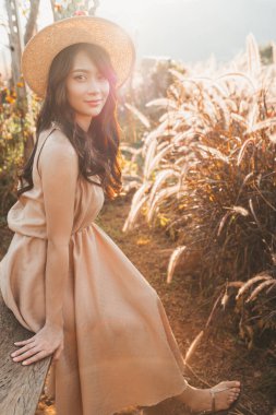 Portrait of asian happy young woman in hat among spikelets in Mon Jam,Thailand