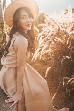 Portrait of asian happy young woman in hat among spikelets in Mon Jam,Thailand