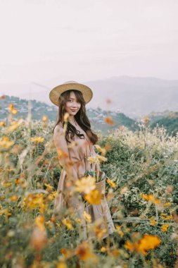 Portrait of asian happy young woman in a hat in flower field in mountains in Mon Jam,Thailand