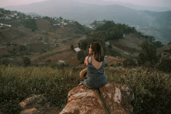 Thai woman in dress and straw hat is sitting on a stone in mountains in Mon Jam — Photo