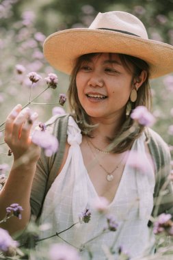 Taylandlı kadın çiçek tarlasında yürüyor.