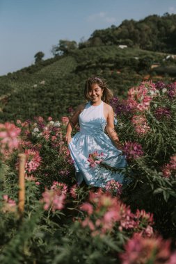 Taylandlı kadın çiçek tarlasında yürüyor.