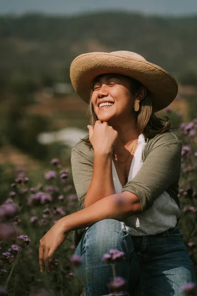 Thai woman is sitting on a stump in flower field — 스톡 사진