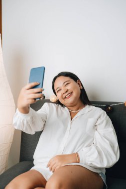 Evde akıllı telefon kullanan güzel bir Asyalı kadın.