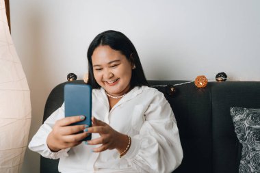 Evde akıllı telefon kullanan güzel bir Asyalı kadın.