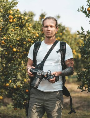 Elinde video kamerayla turuncu bir bahçede duran bir kameraman.