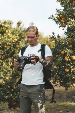 Elinde video kamerayla turuncu bir bahçede duran bir kameraman.