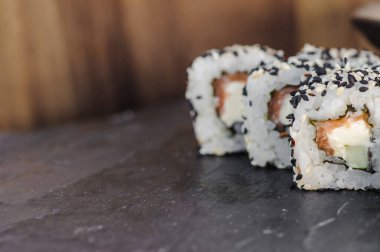 Japon suşisi Philadelphia 'yı siyah taşın üzerinde yuvarlıyor. Yüksek kalite fotoğraf