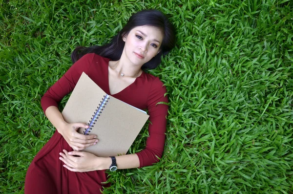Femme couchée sur l'herbe verte avec livre — Photo