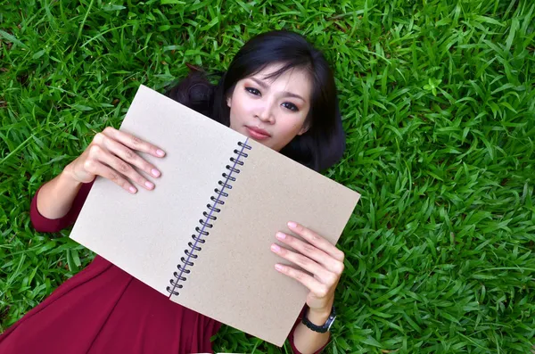 Frau liegt mit Buch auf grünem Gras — Stockfoto