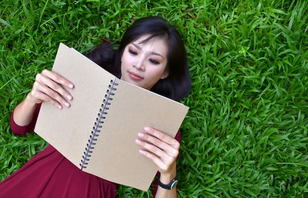 Femme couchée sur l'herbe verte avec livre — Photo