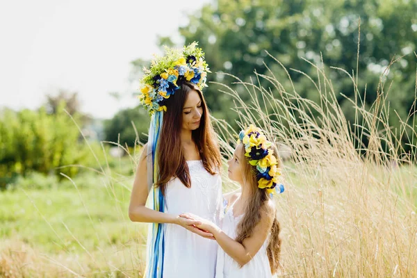 ウクライナの伝統的な花輪の母と娘頭の青とフィールドのウクライナの黄色の旗で ウクライナ独立国旗掲揚日 憲法の日だ 8月24日 愛国的な休日だ 女と子 — ストック写真