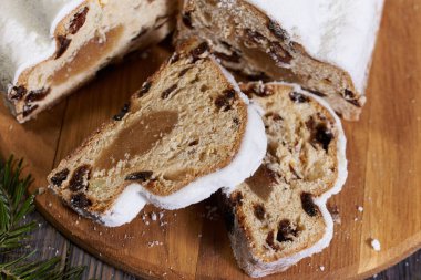 Ahşap arka planda Noel çalıntısı. Geleneksel yılbaşı Alman tatlıları parçalara ayrılmış. Fındıklı kek, badem ezmeli kuru üzüm ve kesme tahtasında kurutulmuş meyve. Xmas için pişirme