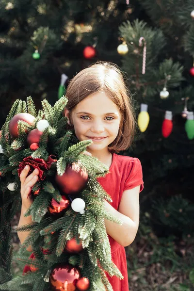 メリークリスマス クリスマスリースとサンタの帽子の幸せな面白い子供の女の子の肖像画 ハッピー ホリデー 妖精の魔法 幸せな子供は休日を楽しんでいる 7月のクリスマス — ストック写真