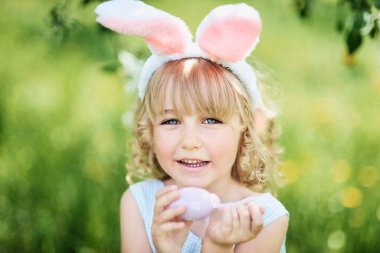 Paskalya yumurtaları ve bahçede tavşan kulakları ile sevimli komik kız. paskalya kavramı. Paskalya yumurtası avında gülen çocuk