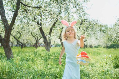 Cute funny girl with Easter eggs and bunny ears at garden. easter concept.