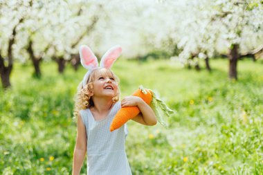 Cute funny girl with Easter eggs and bunny ears at garden. easter concept.
