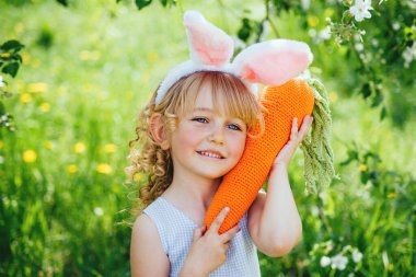 Cute funny girl with Easter eggs and bunny ears at garden. easter concept.