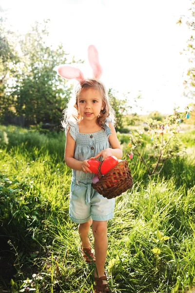 Baby with basket full of colorful eggs. Easter egg hunt. — Stock Photo, Image