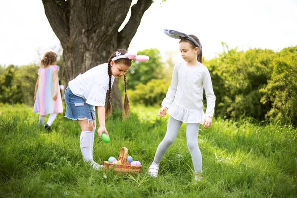 Grupa dzieci noszących królicze uszy biegnie odebrać kolorowe jajko na Easter Egg Hunt w ogrodzie. — Zdjęcie stockowe